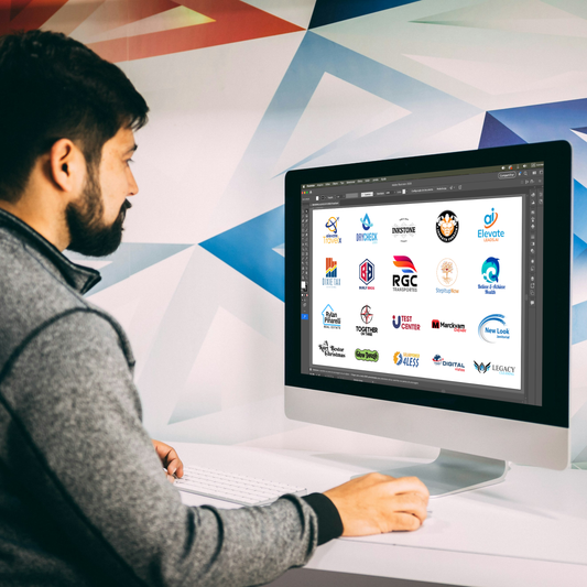 Person using a computer with various logo images on the screen against a colorful geometric-patterned wall.